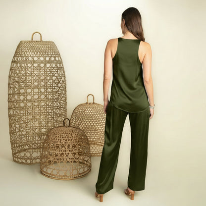 Woman in a green outfit standing next to woven lanterns on a plain background